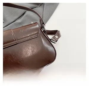 Détail du sac vintage marron foncé en similicuir avec rivets métalliques argentés