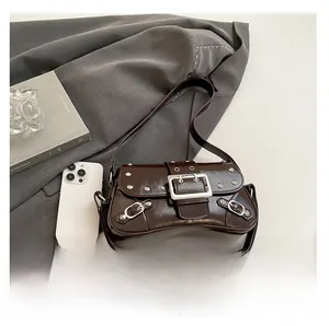 Détail du sac bandoulière en cuir marron brillant avec rivets et boucles argentés
