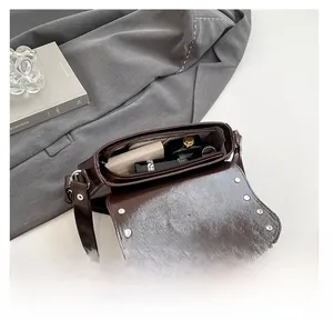 Détail de l'intérieur du sac vintage marron montrant l'espace de rangement et les rivets