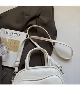 Detail of white bowling bag with wavy stitching, silver hardware, and long shoulder strap