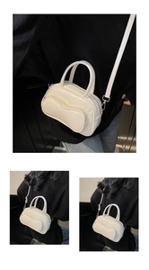 Detail view of a cream-colored PU leather bowling bag showing handles and silver metal hooks