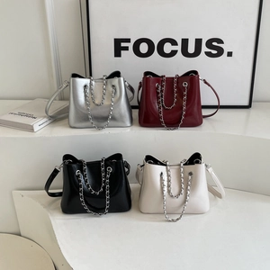 Detailed display of glossy bucket bags in silver, burgundy, black and off-white with chains