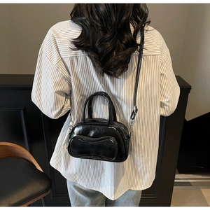 Vue arrière d'un petit sac Boston noir brillant porté sur un t-shirt rayé