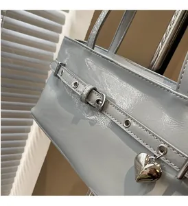 Detail of light blue glossy patent leather bag with silver heart charm and metal eyelets
