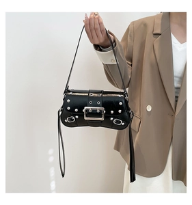 Macro detail of black leather shoulder bag featuring silver rivets and large metal buckle