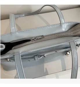 Detail view of smooth silver zipper and heart pendant on blue patent leather handbag