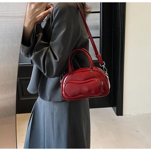 Detailed view of the stylish red patent leather pillow handbag with sturdy top handles.