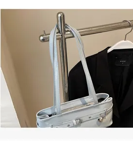 Detail view of the silver glossy leather underarm bag featuring a metallic heart charm
