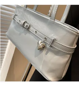 Detail of light blue patent leather bag with silver heart charm and belt buckle