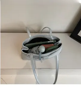 Internal view of the glossy grey shoulder bag showing large capacity for daily items