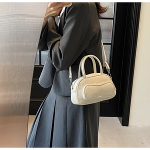 Close-up of cream white bowling bag featuring refined stitching and adjustable strap
