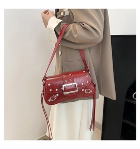 Detail of red punk-style underarm bag with silver rivets and metal buckle design