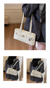 Détail du sac blanc brillant avec boucle décorative et pendentif en forme de cœur argenté