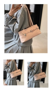 Détail du sac sous le bras en cuir verni rose brillant avec pendentif cœur et boucle