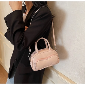 Mini sac Boston rose brillant avec poche zippée ondulée porté par un mannequin