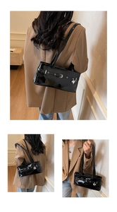 Détail du sac en cuir verni noir brillant avec œillets et pendentif en cœur