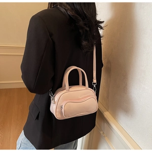 Detailed view of light pink patent leather bowling bag with wavy zip pocket and silver hardware