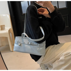 Close-up of light blue patent leather underarm bag with silver heart charm detail