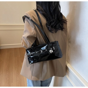 Detail of glossy black patent leather shoulder bag with silver heart pendant and buckles