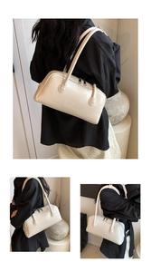 Detailed view of cream-colored shoulder bag featuring dual zipper and embossed logo