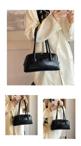 Detail of vintage black PU leather shoulder bag with glossy pleated texture on cream suit
