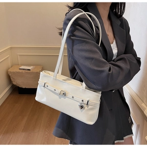 Détail du sac sous le bras blanc crème brillant avec pendentif cœur sur le mannequin