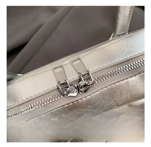 Close-up of dual silver zippers and textured metallic leather on a Boston bag