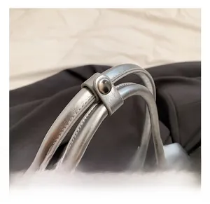 Detail of silver baguette bag handle connection with polished metallic buckle closure
