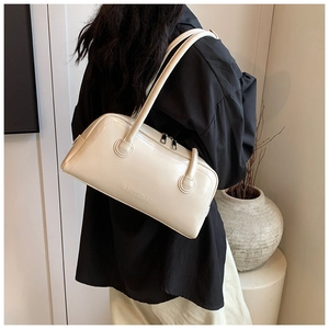 Detail of cream shoulder bag featuring an embossed logo on premium textured leather
