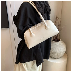 Close-up of a creamy white Boston handbag with embossed logo and metal double zippers