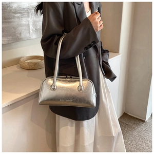 Close-up of metallic silver Boston bag featuring slim handles and top zipper detail