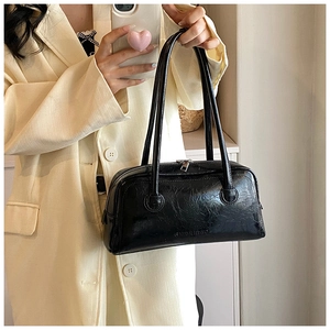 Close-up of black pleated PU leather texture and embossed logo on baguette shoulder bag