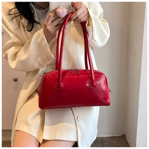 Close-up of a red glossy Boston bag with textured synthetic leather and zip closure