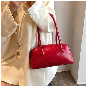 Close-up of red glossy shoulder bag with vintage crinkled leather texture and stitching
