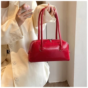 Close-up of a glossy deep red leather baguette bag featuring embossed SHINIUBAG text