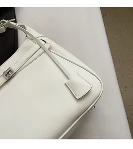 Macro view of white leather tote bag featuring a silver metal twist lock and fine texture