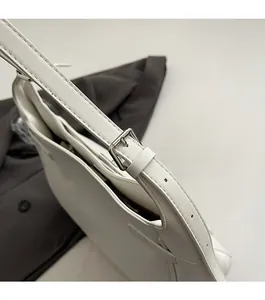 Close-up of premium white leather tote bag with silver metal buckle and refined stitching