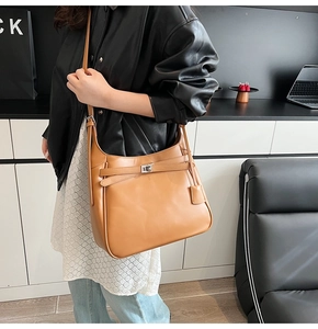 Close-up of brown leather bucket bag featuring silver turn-lock and bottom studs