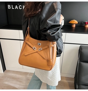 Detail view of large tan tote bag with X-shaped leather straps and silver buckle
