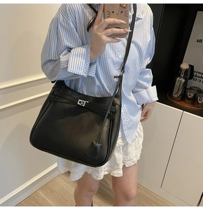 Close-up of black leather bucket bag featuring a silver square twist lock and decorative strap