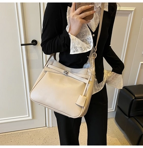 Close-up of beige hobo bag with leather straps, silver twist-lock and protective base studs