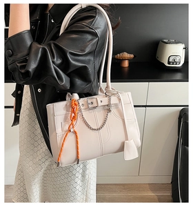 Dettaglio della borsa tote beige con cordoncino arancione e catena d'argento chic