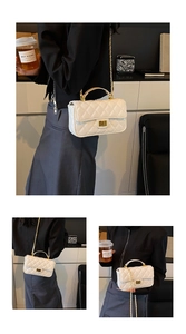 Detail of white quilted patent leather flap bag with gold chain strap and turn-lock