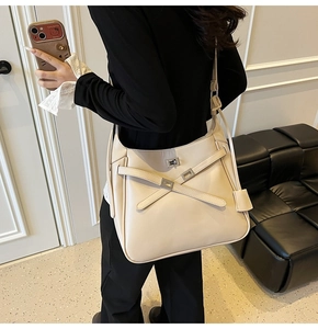Detail view of large beige leather bucket bag with silver twist lock and crossbody strap