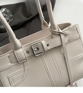 Dettaglio della borsa tote beige con texture in pelle pregiata e fibbia in argento