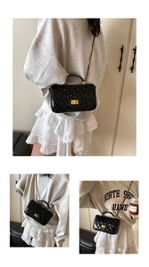 Detail of glossy patent leather crossbody bag with diamond quilting and chain strap