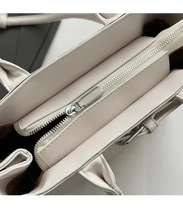 Dettaglio ravvicinato della cerniera in metallo argentato su borsa tote in pelle beige