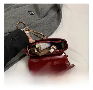 Interior capacity detail showing red patent leather mini bag with chain strap and zipper