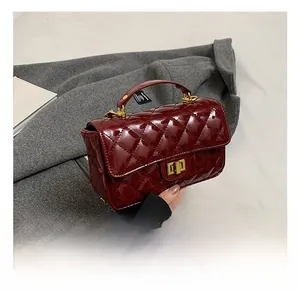Detail view of burgundy patent leather bag with quilted pattern and gold turn-lock