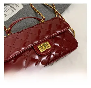 Detail of burgundy patent leather handbag with diamond quilting and gold twist lock